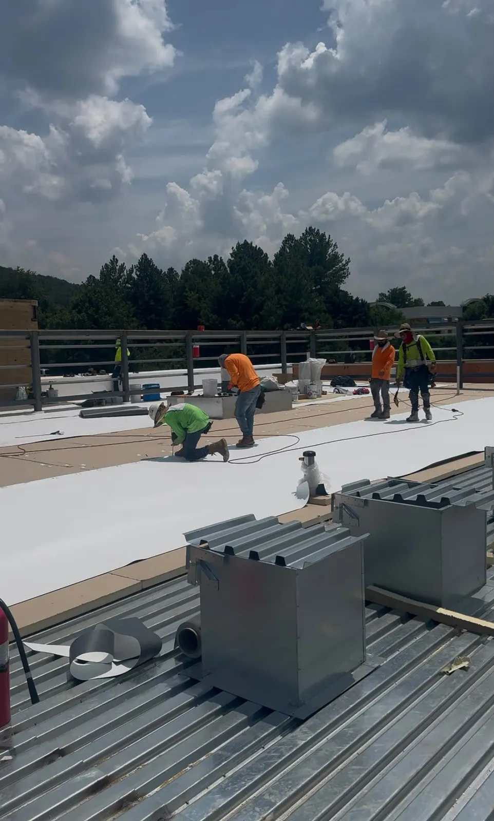 Crew installing TPO roofing over metal decking on a commercial project