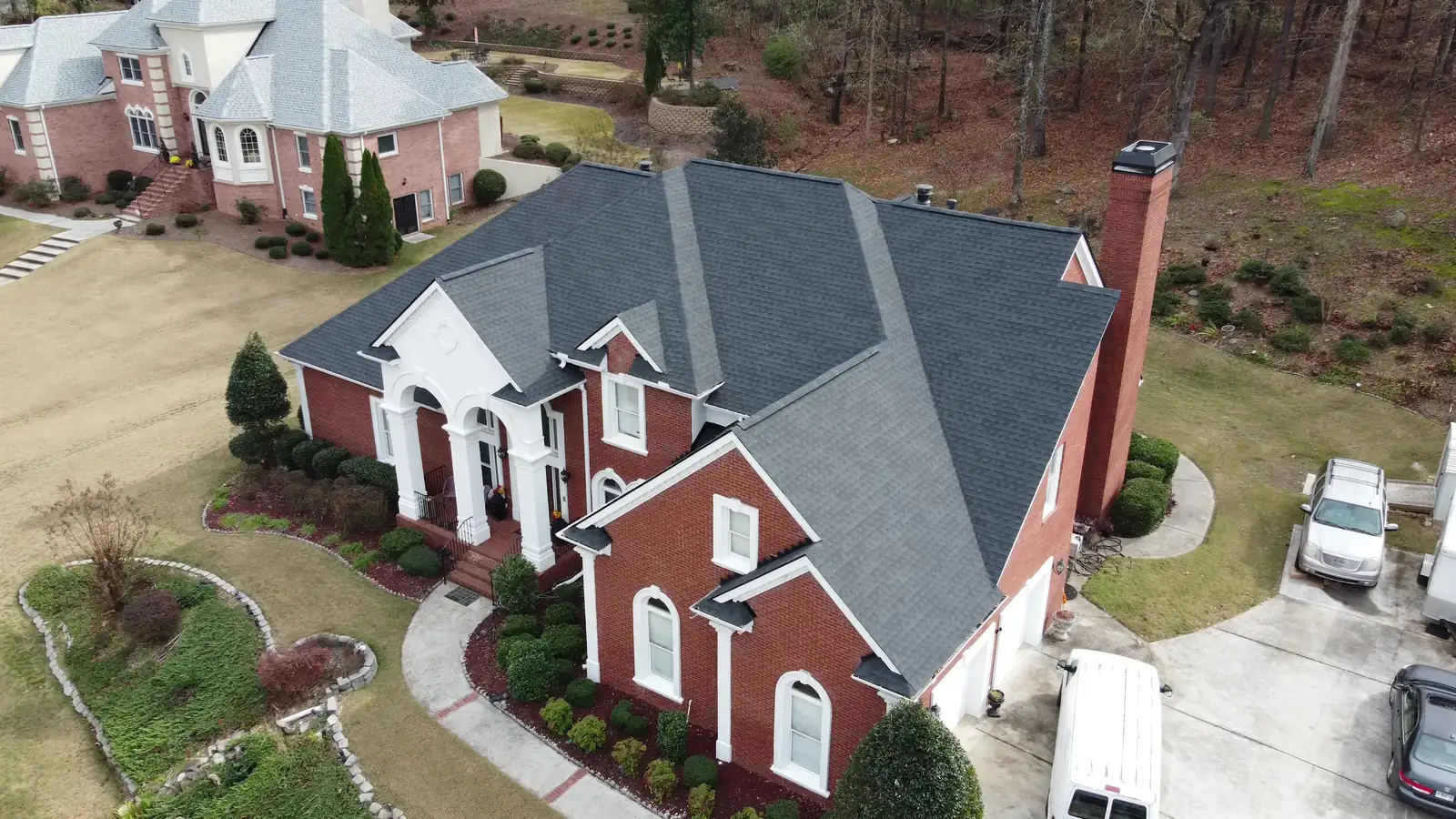 Aerial view of a new dark gray shingle roof on a two-story brick home