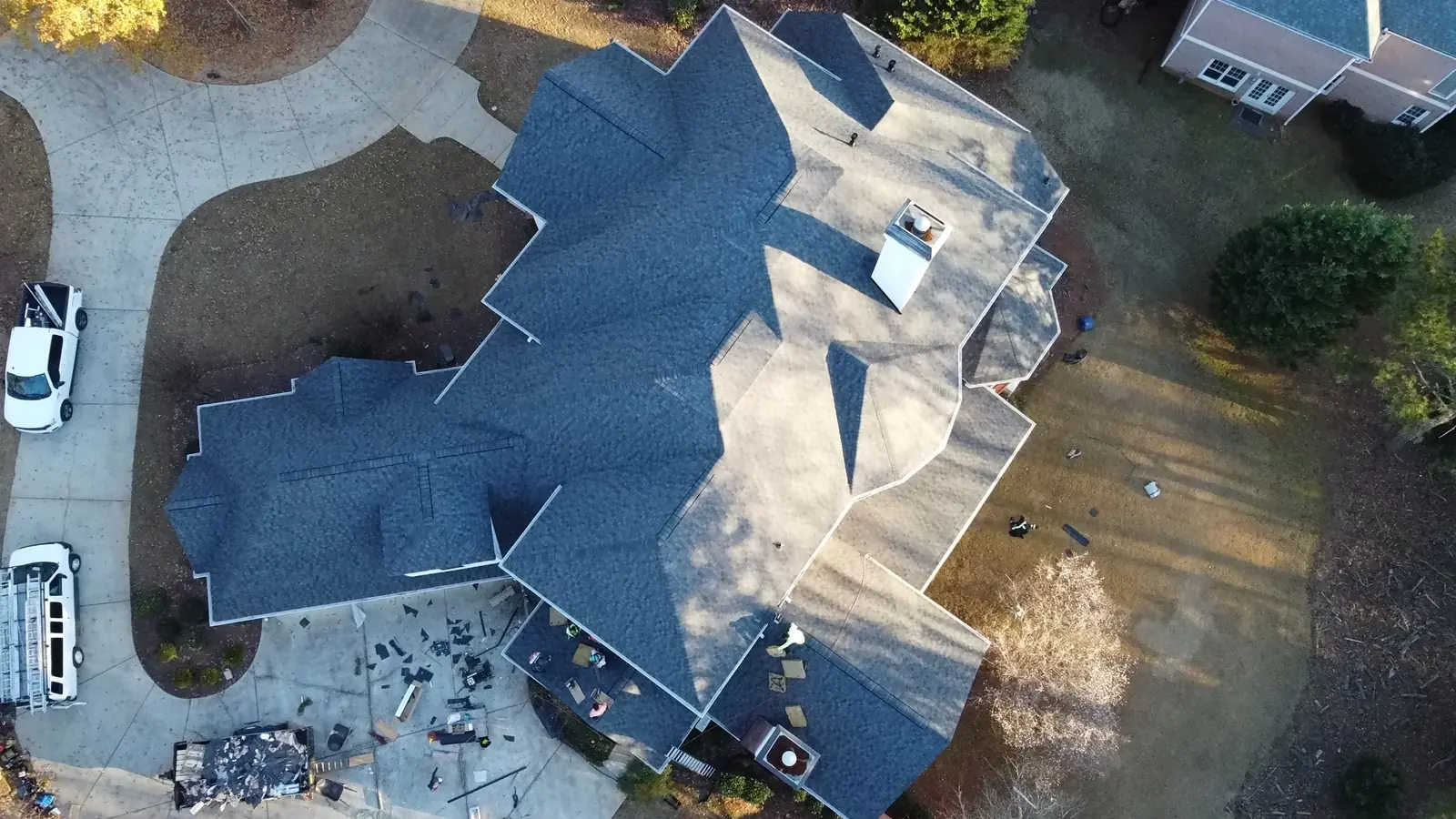 Drone view of a roof replacement in progress, with tear-off debris in the driveway